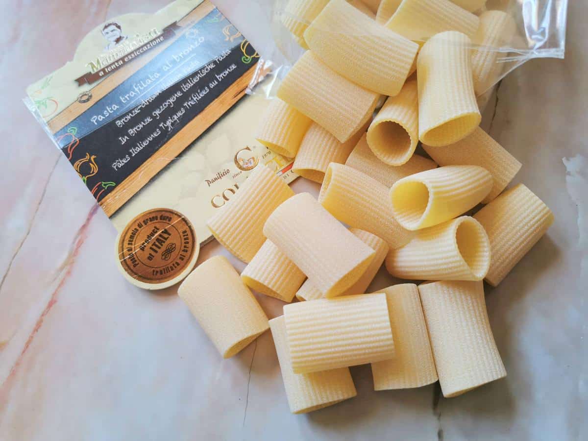 Dried paccheri birigati (double grooved) on marble work top.