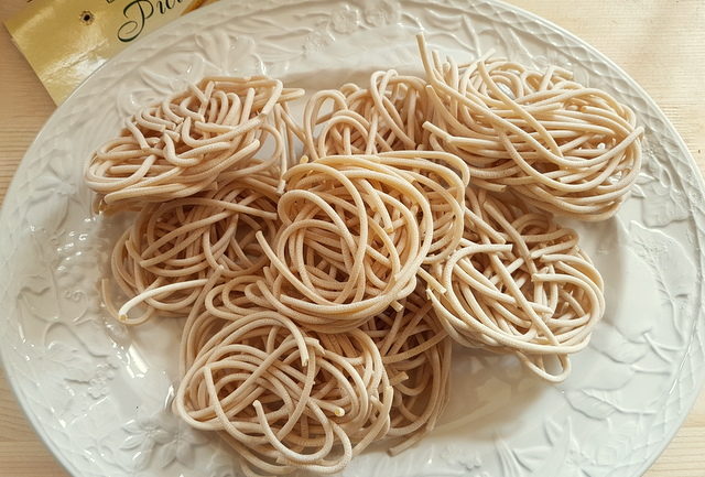 dried pici pasta nests on white plate