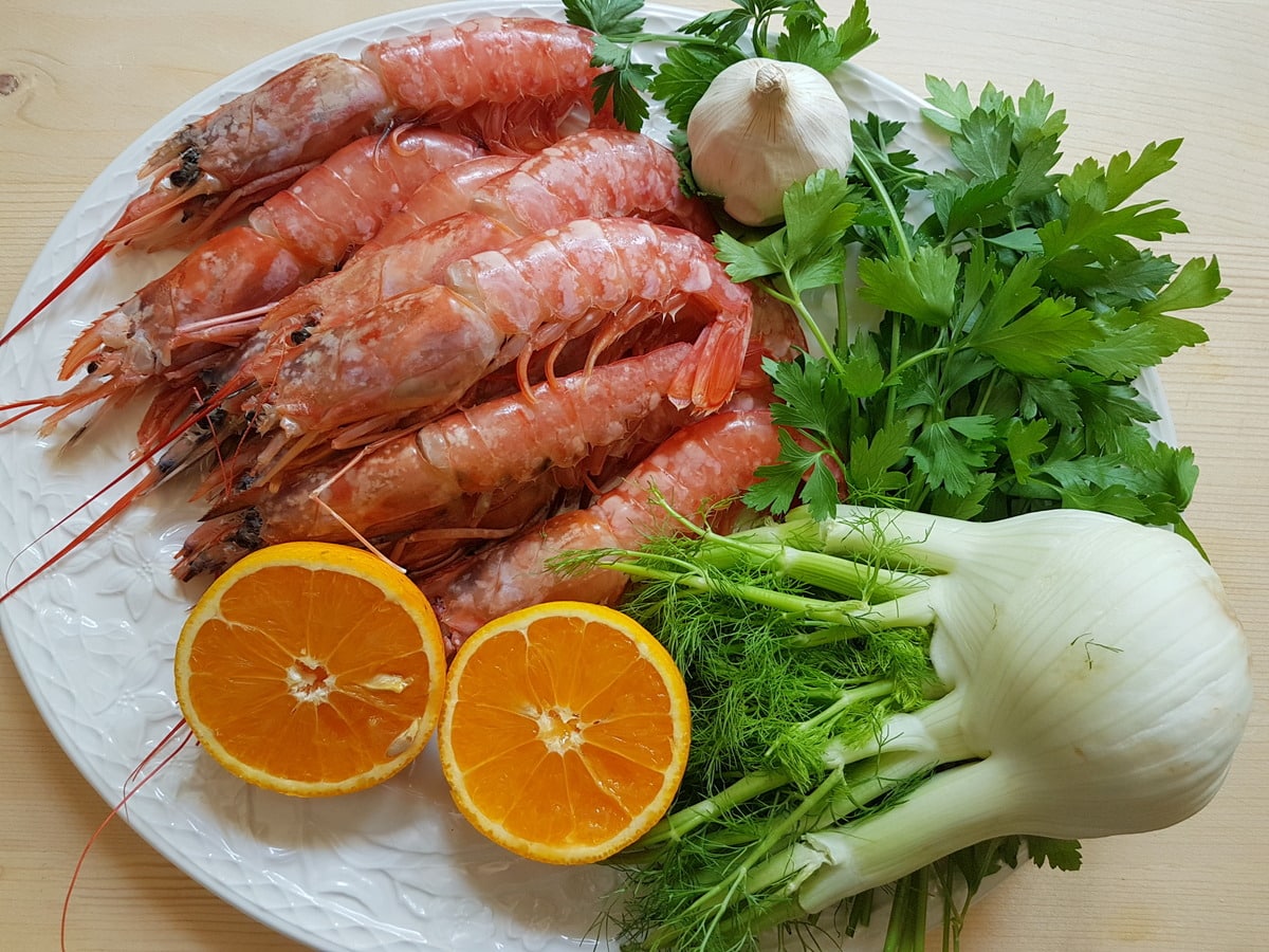 Large prawns, fennel, orange, garlic and parsley on a plate.