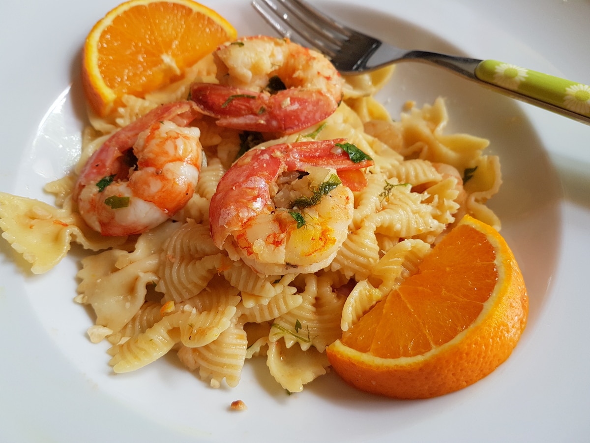 Prawn pasta in a bowl with orange slices.