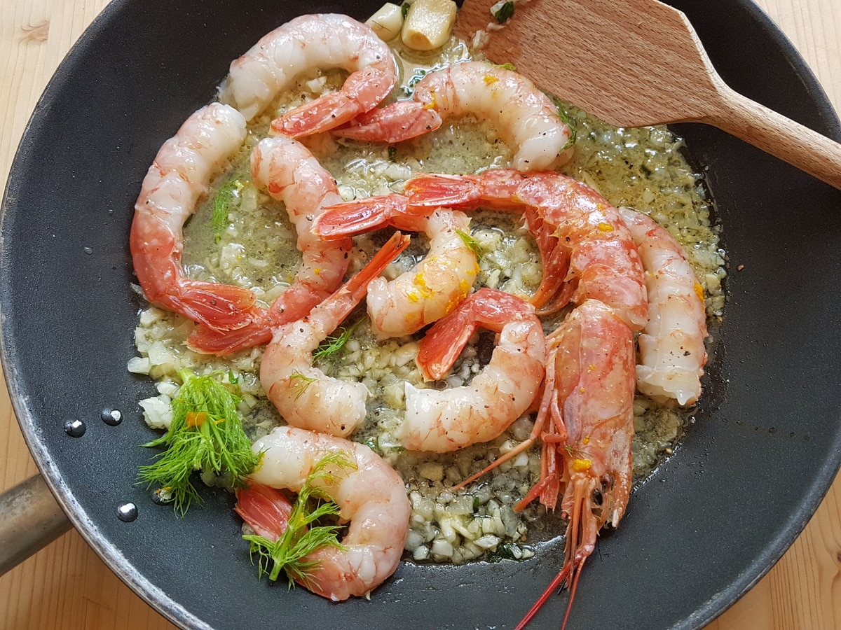 Prawns cooking in a pan with white wine, fennel, garlic and olive oil.