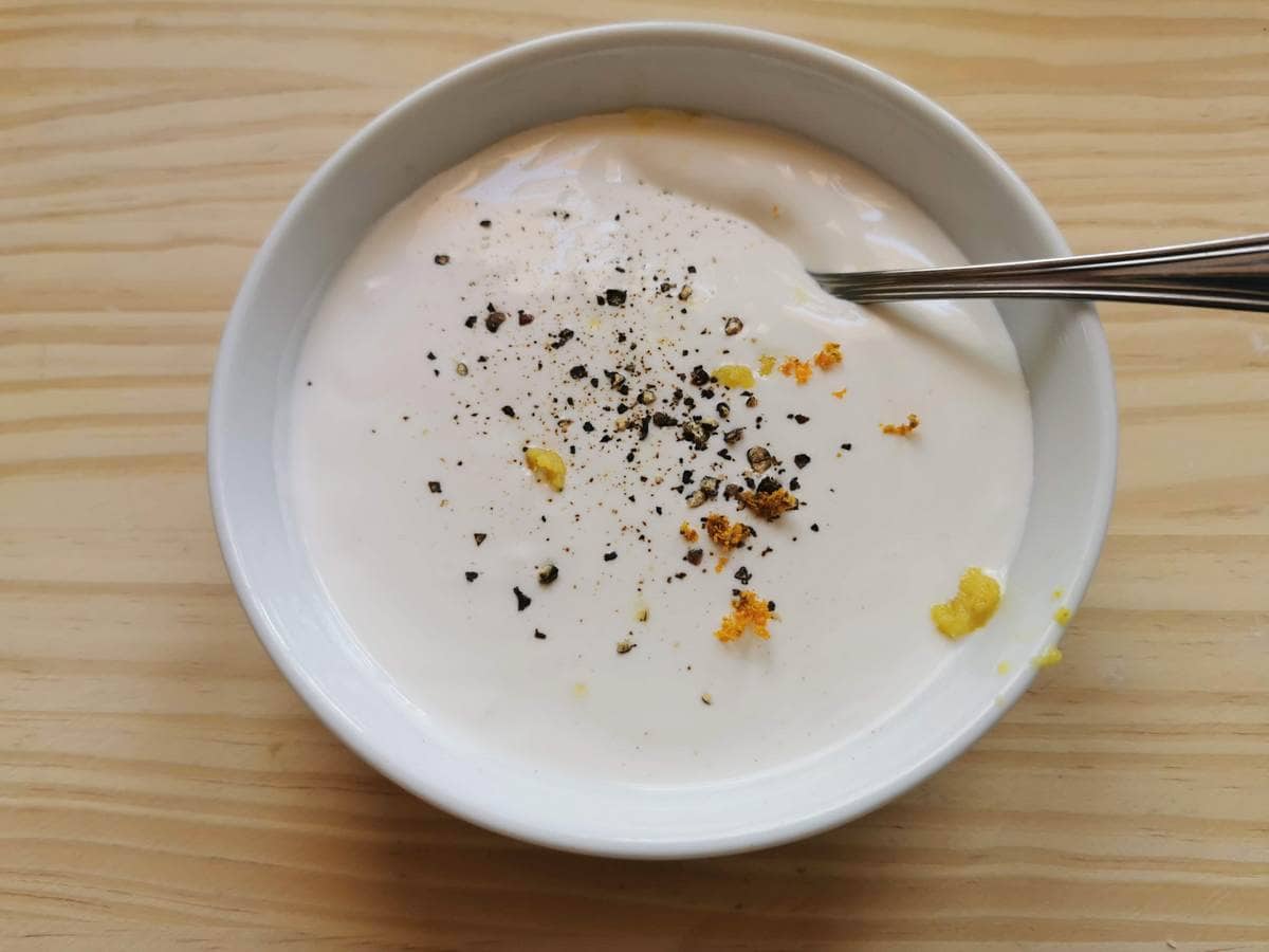 orange zest, groung black pepper and grated ginger on top of heavy cream in white bowl