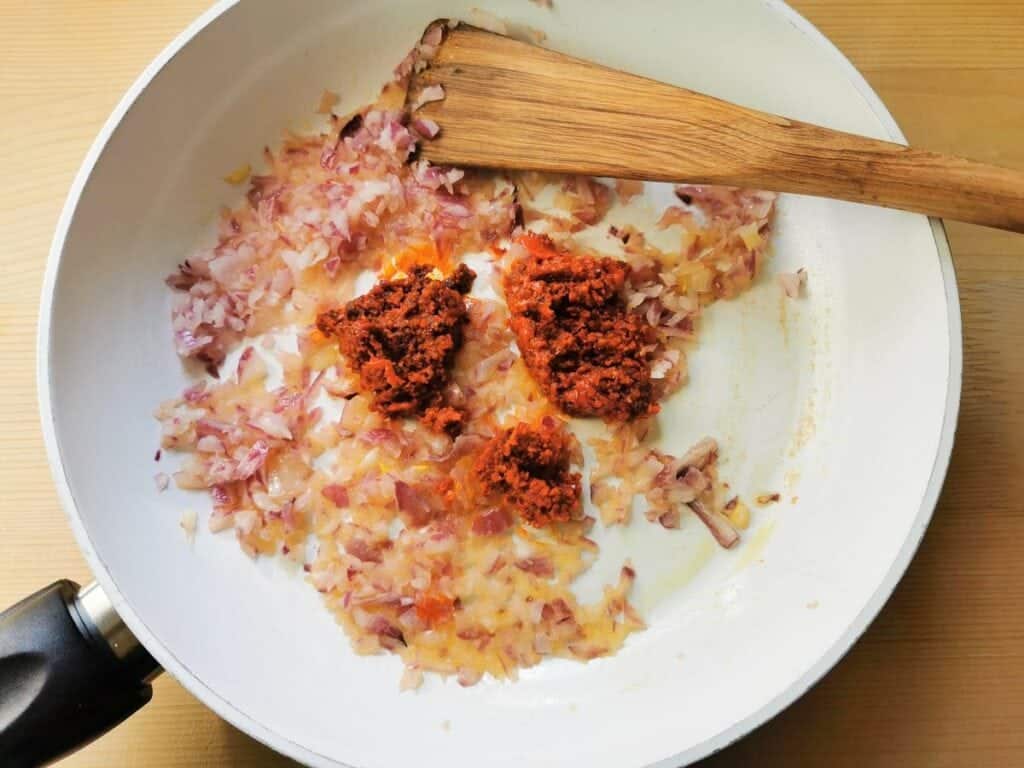 nduja added to chopped onions cooking in a pan