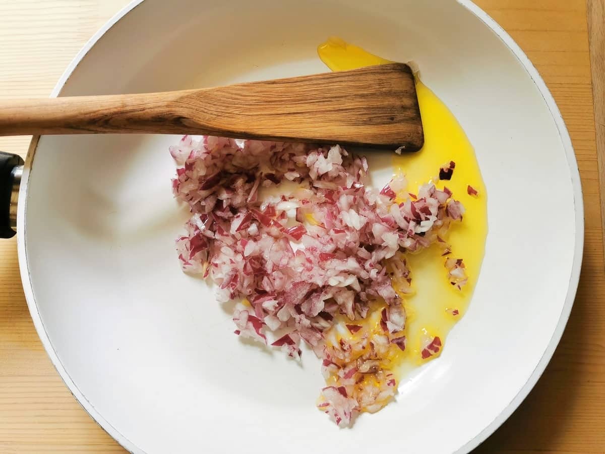 Peeled and chopped red onion in frying pan with olive oil.
