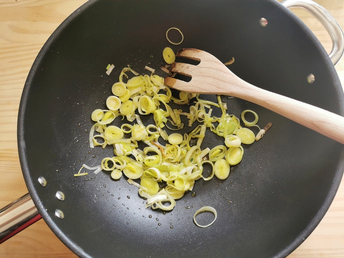 Sliced leek in deep frying pan with olive oil.