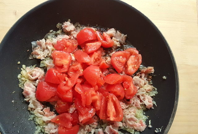 peeld tomatoes, pancetta and onions cooking in frying pan