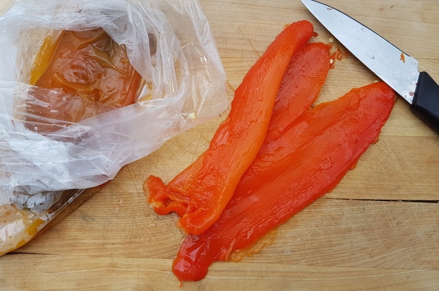 peeled red peppers on chopping board