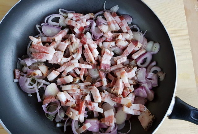 sliced shallots and guanciale cooking in frying pan