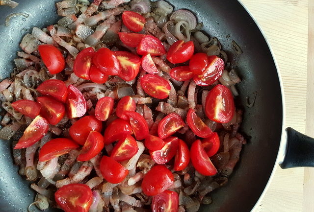 chopped tomatoes, sliced shallots and guanciale cooking in frying pan