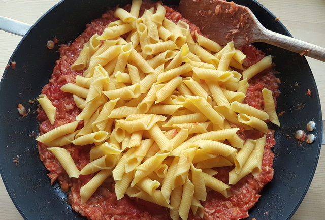 cooked garganelli pasta added to tuna Bolognese in frying pan
