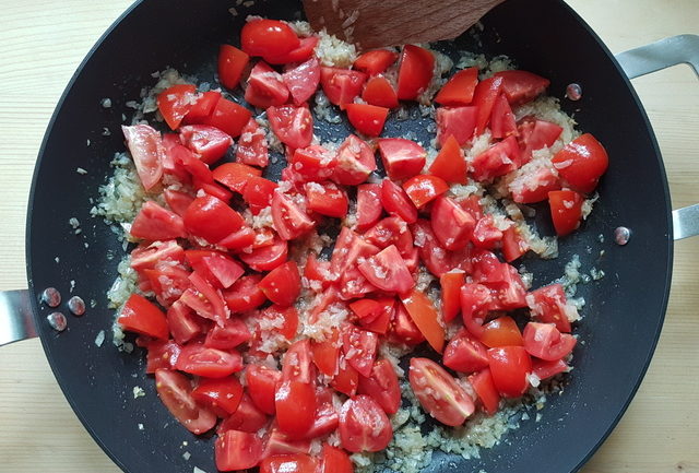 chopped tomatoes and onion cooking in frying pan