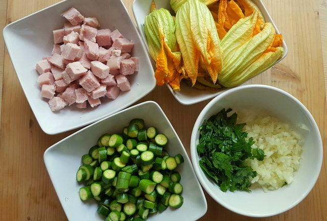 Ingredients for pasta with zucchini flowers, saffron and ham prepared in small white bowls