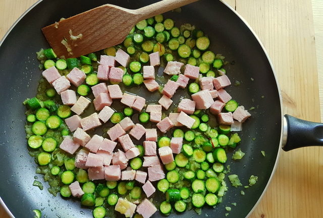 onions, zucchini and cooked ham cubes cooking in frying pan