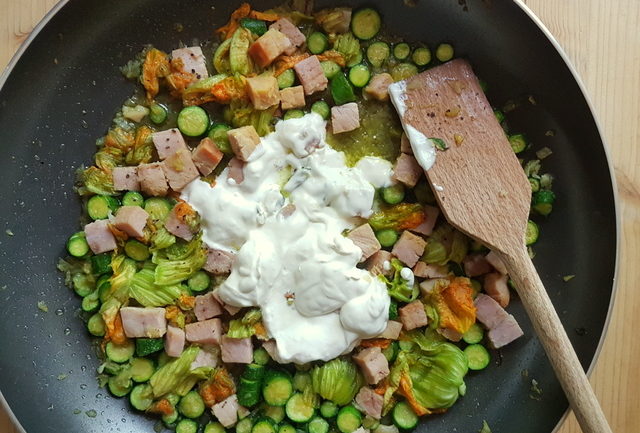 sauce cooking in frying pan for pasta with zucchini flowers, saffron and ham