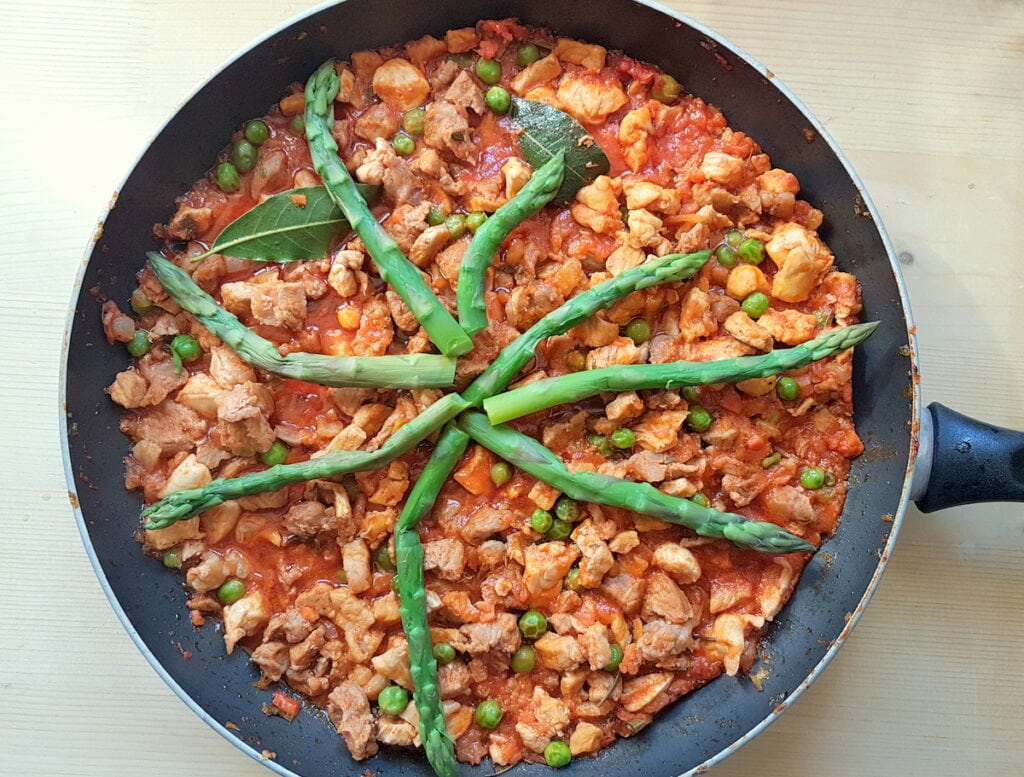 ready spring mixed meat ragu with cooked asparagus in skillet