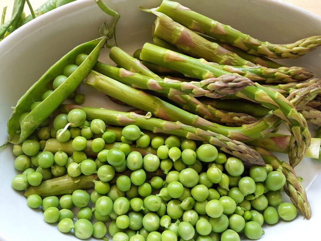 fresh asparagus and peas in white bowl