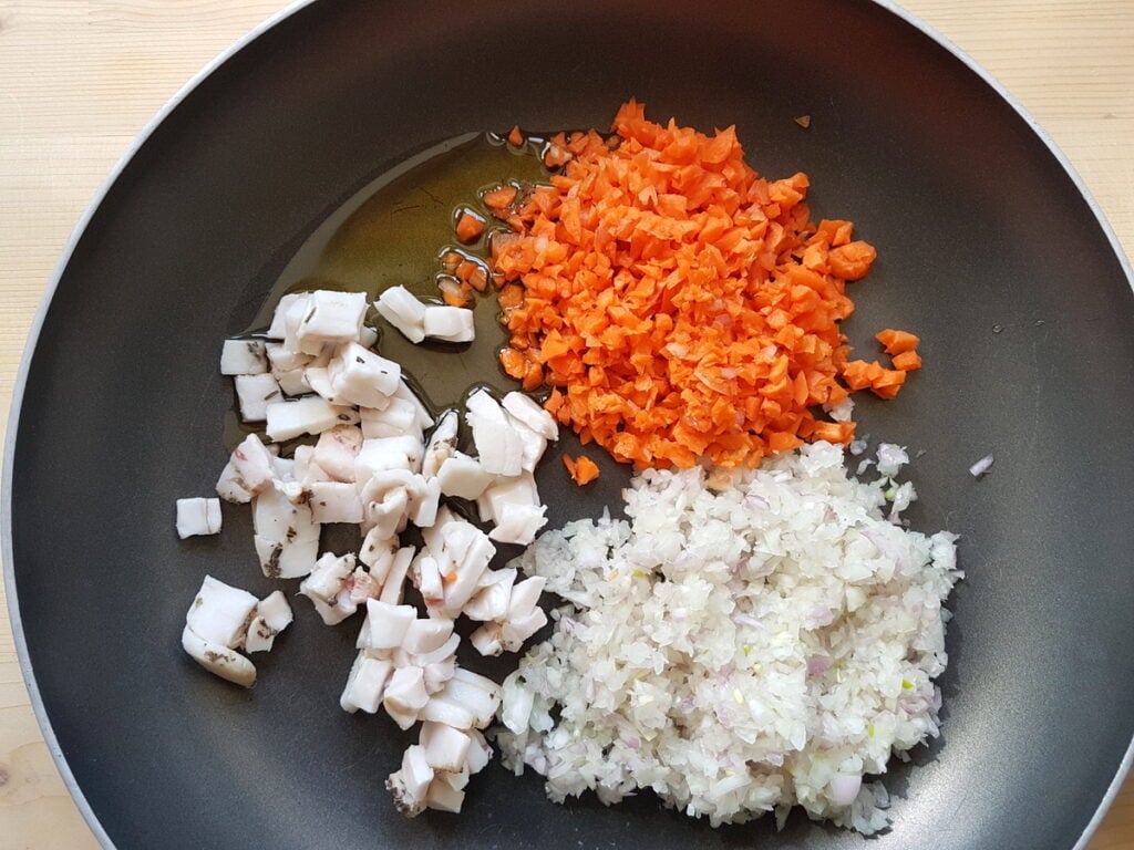 chopped lardo, carrots and onions in skillet with olive oil