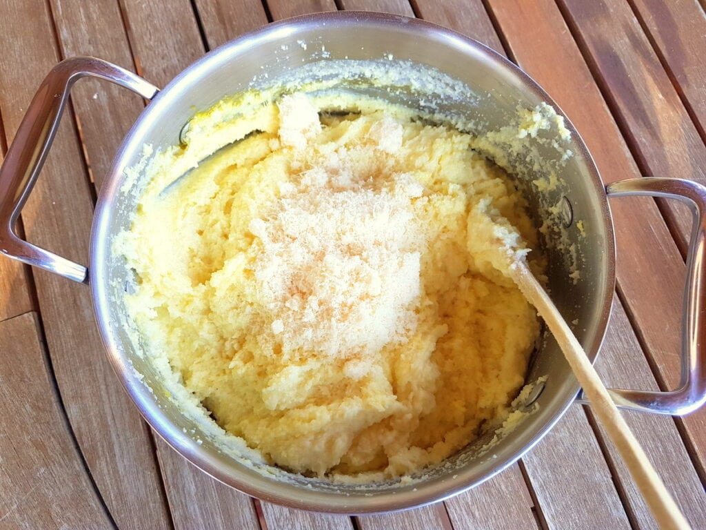 grated cheese in saucepan with cooked semolina