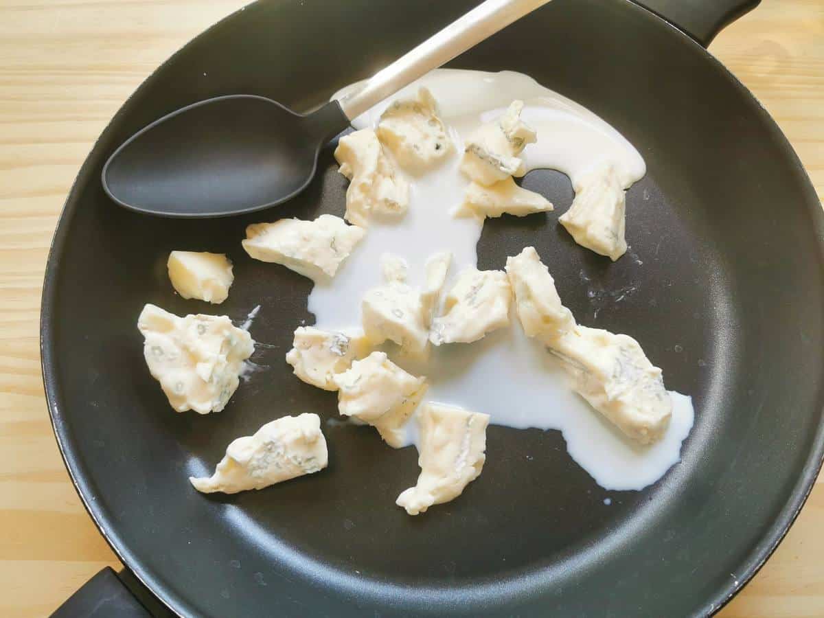 Milk and Gorgonzola pieces in a skillet pan.