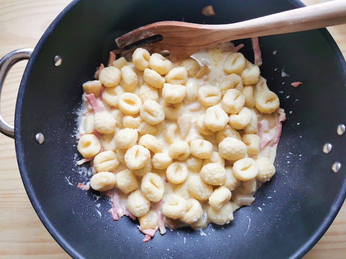 Cooked potato gnocchi in deep frying pan with taleggio sauce.