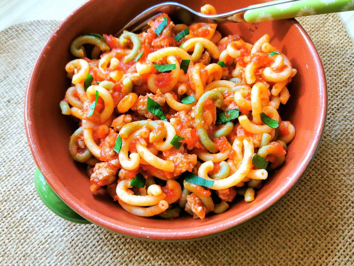 A serving of gramigna with sausage in a terracotta bowl.