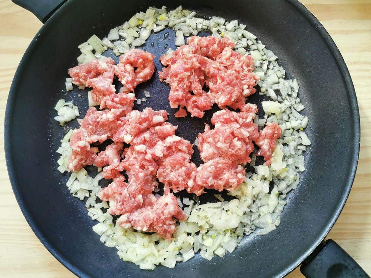 minced sausage and diced onions in a pan