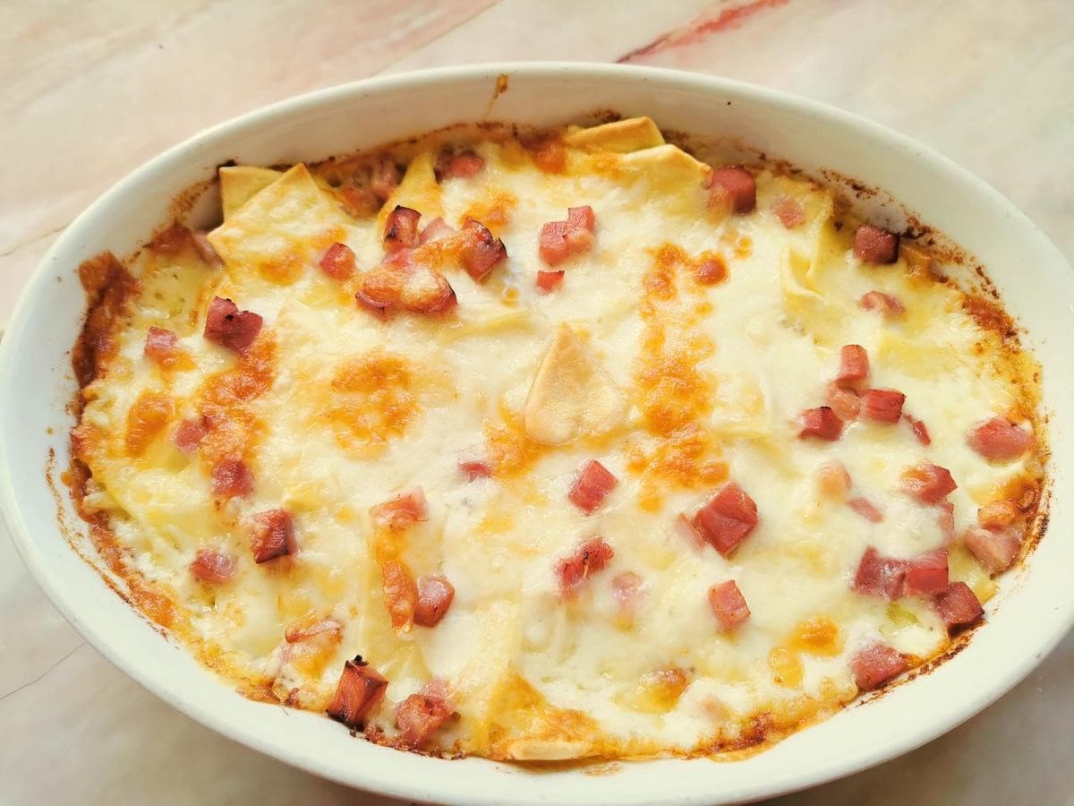 Ham and cheese pasta bake in white oval oven dish.