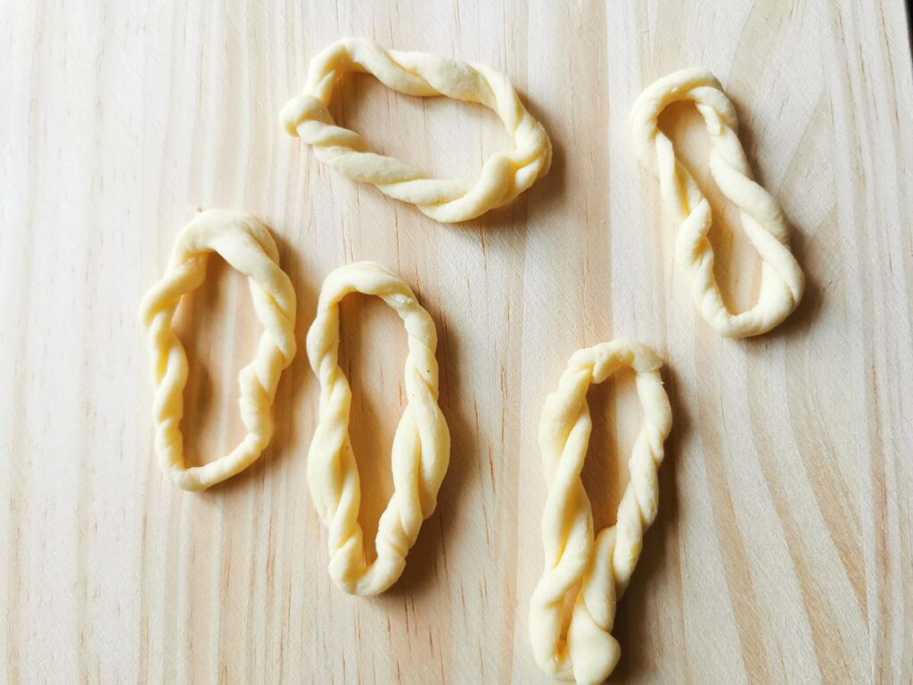 ready braided lorighittas pasta rings on wooden board