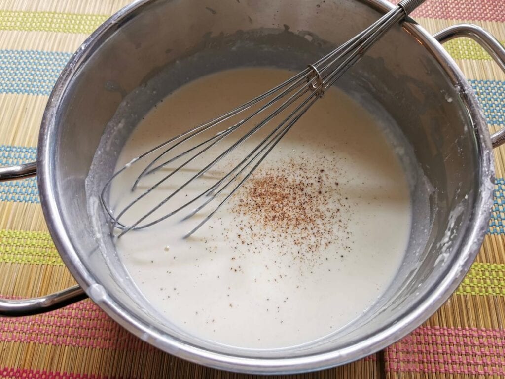 ready béchamel in saucepan with grated nutmeg on top