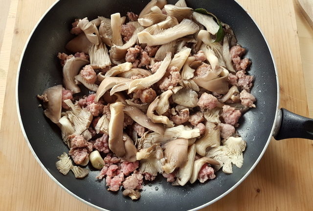 garlic, sausage meat and oyster mushrooms cooking in frying pan