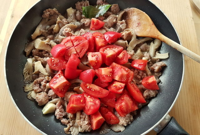 chopped peeled tomatoes, oyster mushrooms and sausage meat in frying pan