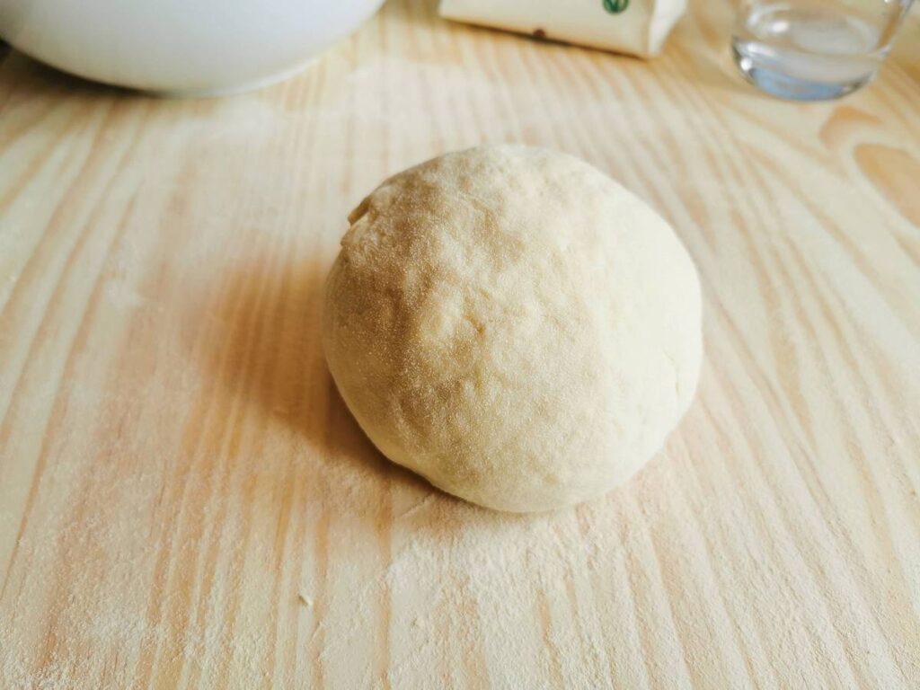 Ball of semolina flour and water dough on wooden pastry board