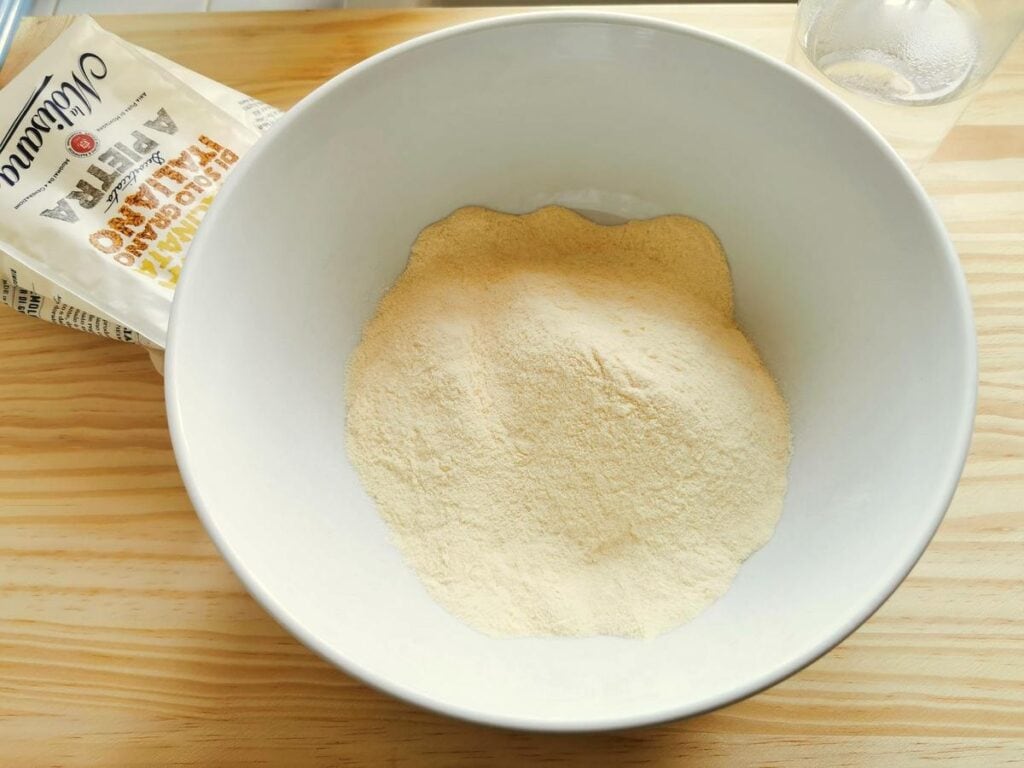 semolina flour in white bowl and salted water in a glass