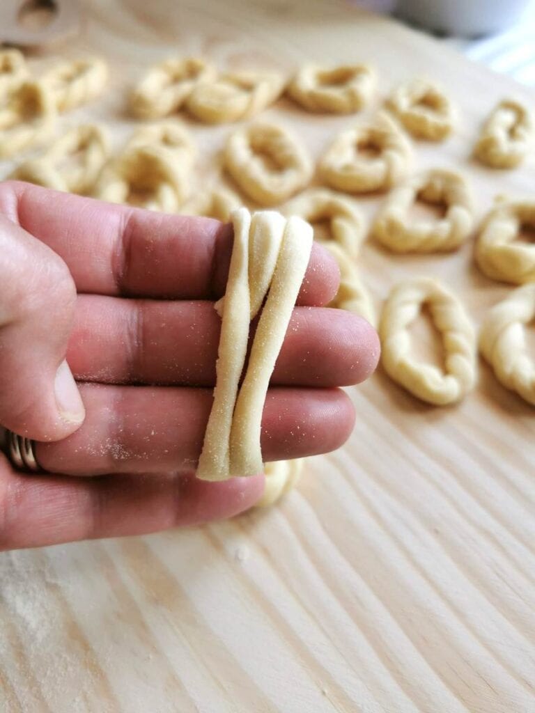 strand of pasta dough wrapped around 3 fingers on a hand