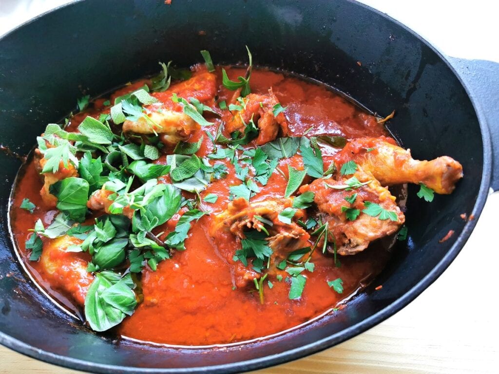 Fresh chopped parsley, basil and sage in Dutch oven with chicken ragu