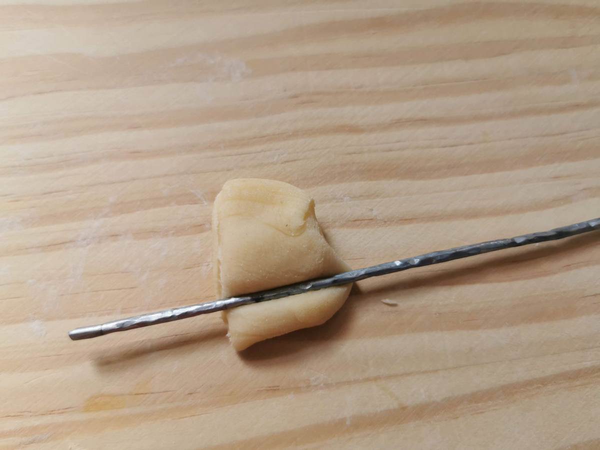 A small piece of pasta dough with a slim iron rod (fero) pressed across it.