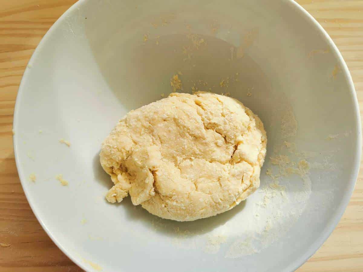 Ball of rough dough in white bowl.