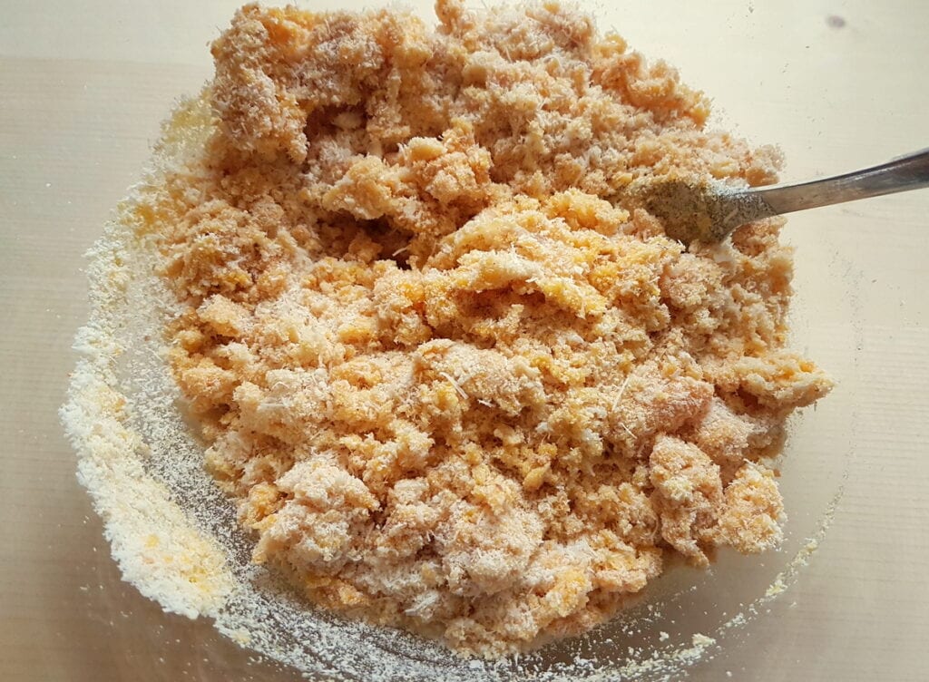 cheese breadcrumbs and eggs mixed together in a glass bowl