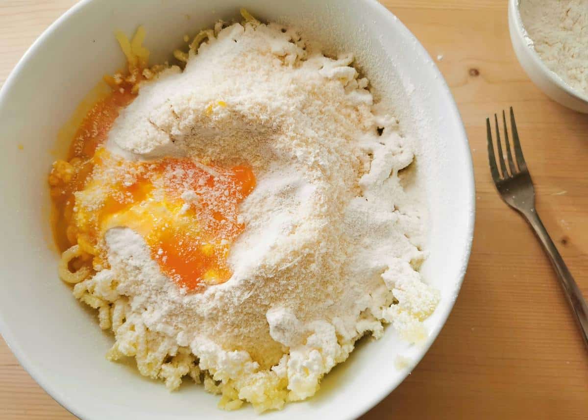 potato, flour, egg and grated Parmigiano in white bowl.