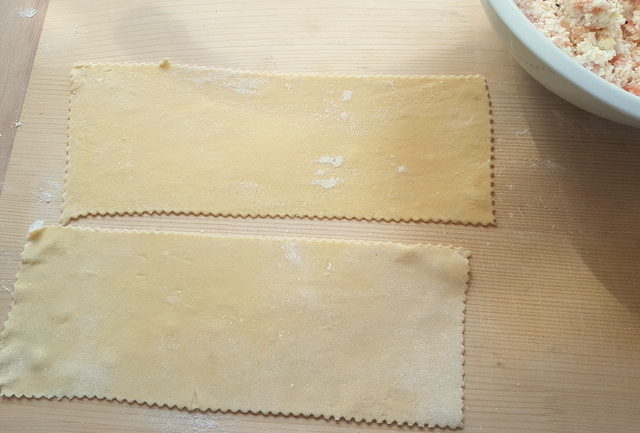 2 rolled out fresh pasta rectangles on wooden board