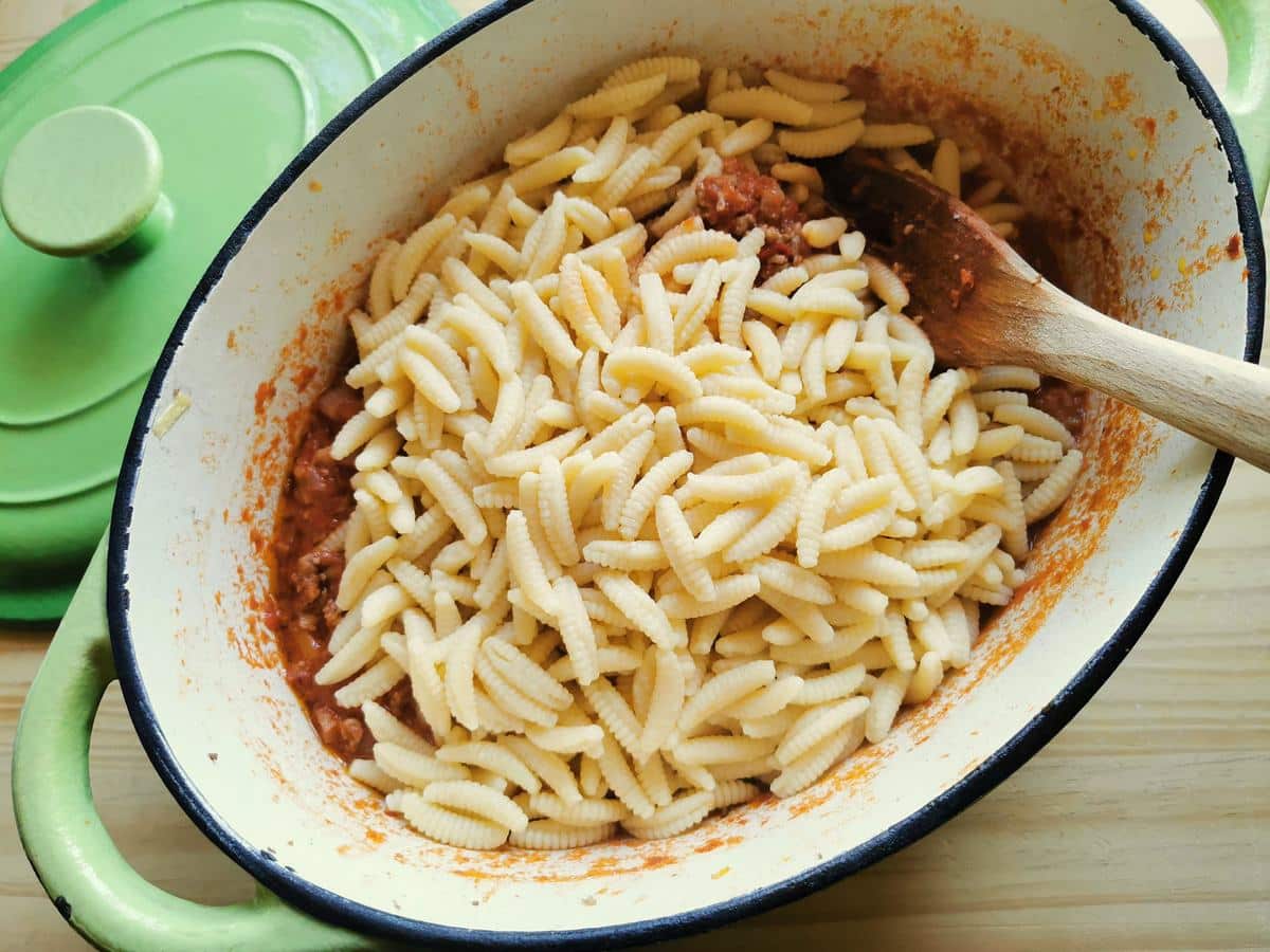 Malloreddus pasta being added to the lamb ragu.