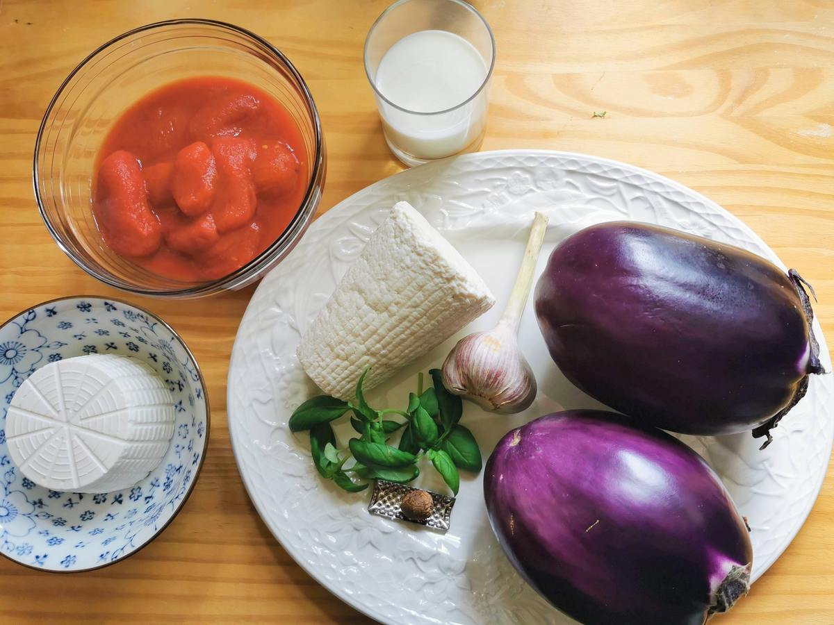 Ingredients for lasagna alla norma on wood worktop.
