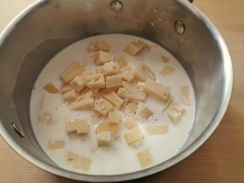 cubes of fontina cheese with milk in saucepan