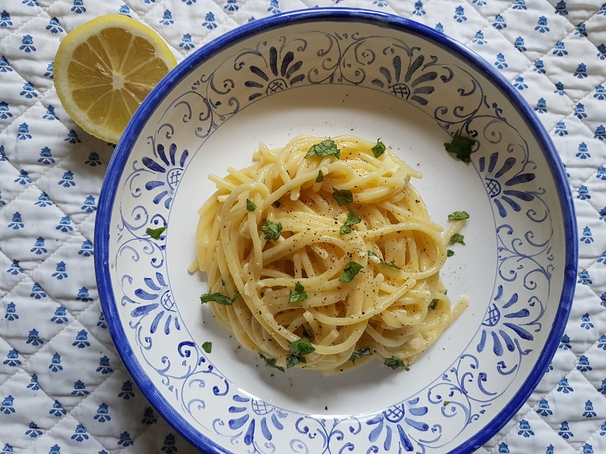 Lemon water pasta in a bowl with a garnish of lemon.