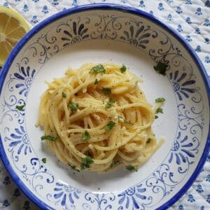 Lemon water pasta in a bowl with a garnish of lemon.