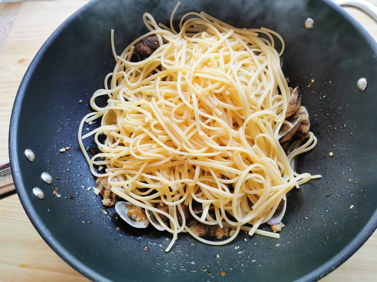 Cooked linguine added to pan with clams.