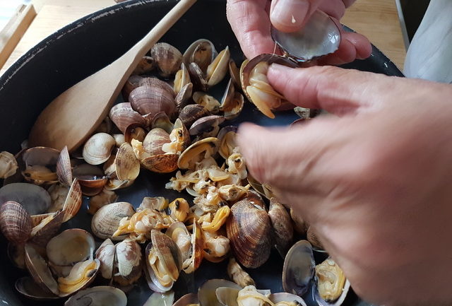 removing cooked clams from their shells for pasta alle vongole