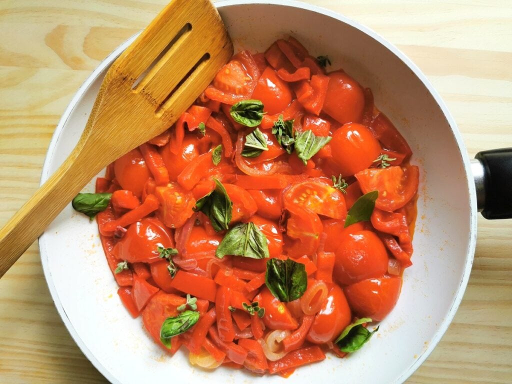 fresh basil, tomatoes, onions and red peppers cooking in frying pan