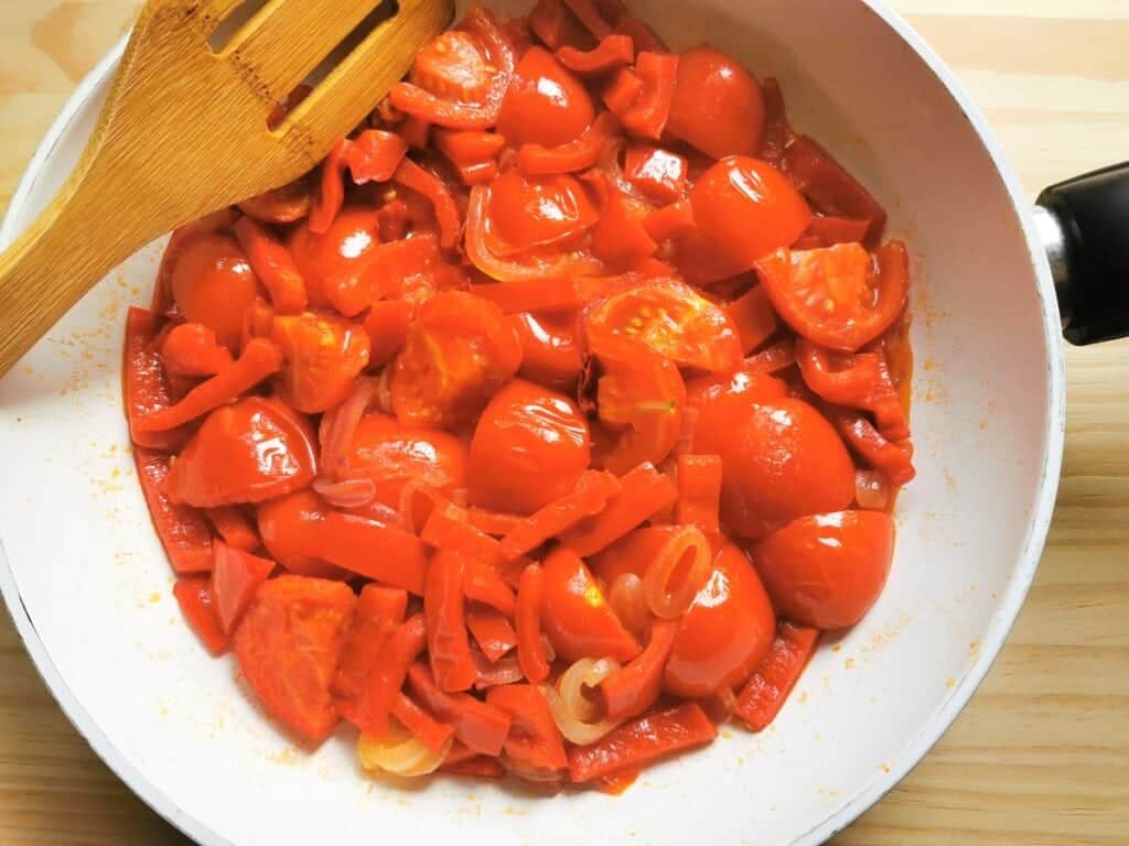 onions, tomatoes and red peppers cooking in frying pan