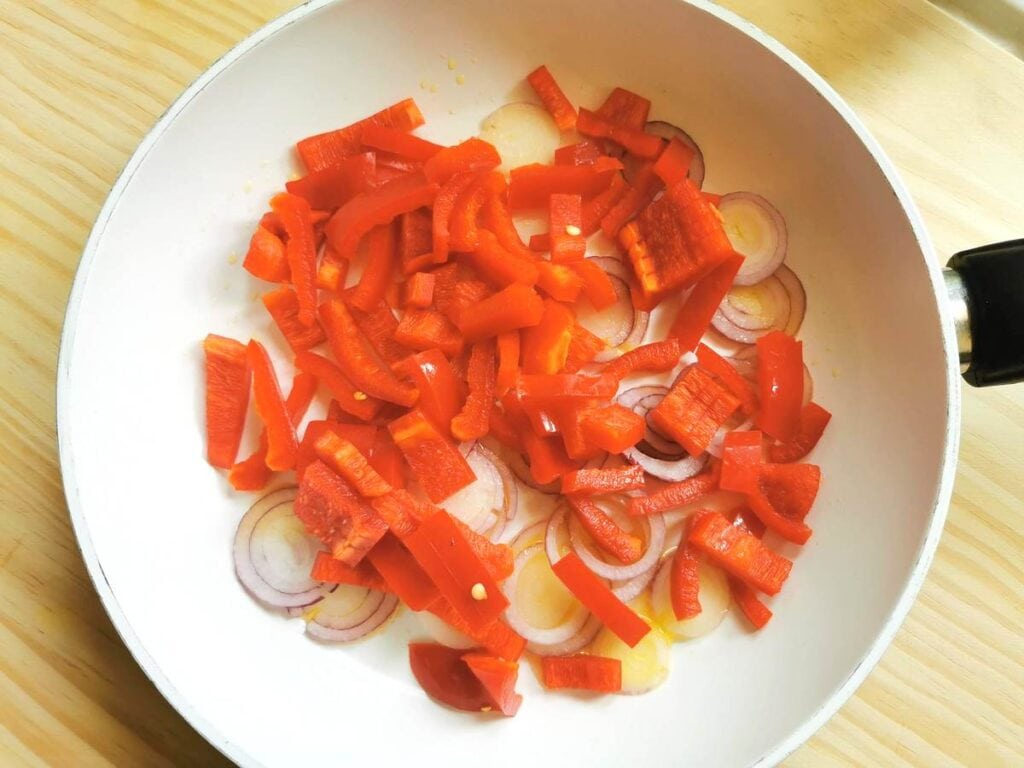 chopped red peppers and onions in frying pan